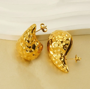 Detailed macro shot of 18K gold teardrop earrings with elegant hammered texture finish
