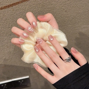 Pink cat-eye press-on nails with white heart design and silver vintage ring accessory