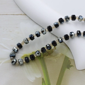 Macro detail of 6mm faceted rondelle glass beads in alternating dark grey and black crystal