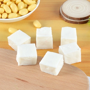 Macro shot of realistic miniature white tofu cubes and soybeans on wooden tray