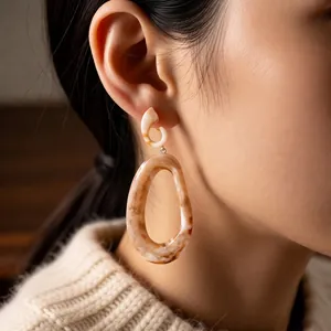Retro acrylic oval drop earrings with brown marble texture worn by a fashion model