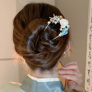 Detail einer Haarnadel mit Muscheln und Perlen in einer traditionellen Hochsteckfrisur