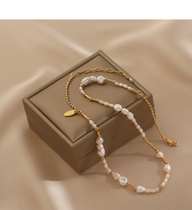 Detail of baroque pearl and gold chain necklace with handmade tag on silk