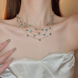 Detail of layered gold necklace featuring elegant turquoise zircon stones on the model neck