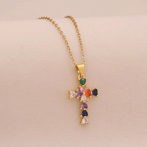 Luxury cross necklace with colorful zircons on golden chain against a neutral background