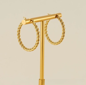 Detailed view of gold twisted rope hoop earrings displayed on a T-shaped jewelry stand