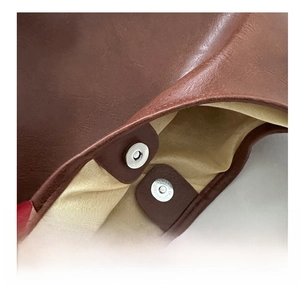 Close-up of the metal magnetic clasp and durable leather texture on a brown tote bag