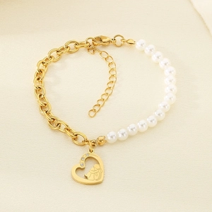 Detail of gold titanium chain bracelet with pearls and engraved heart pendant charms