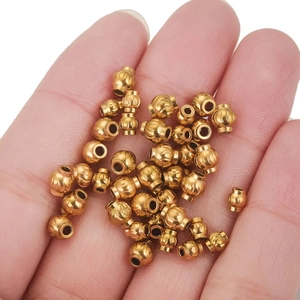 Golden stainless steel lantern beads for DIY jewelry making shown on palm for size scale