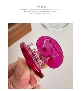 Macro detail of a small magenta acetate hair claw clip with a durable metal spring