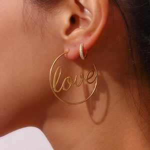 Detail of 18K gold-plated stainless steel hoop earring with Love script on a model ear