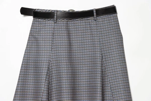 Detailed view of houndstooth midi skirt with a black faux leather belt and textured fabric