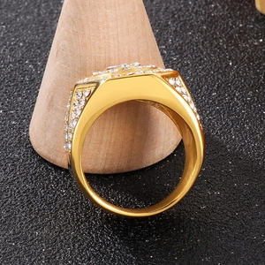 Close-up of a luxury gold-plated hip-hop ring with pavé-set stones on a wooden stand