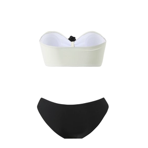 Flat lay of a two-piece bikini set with a white bandeau top and black swim bottoms