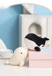 Close-up of soft plush orca and beluga whale toys in a cozy home setting