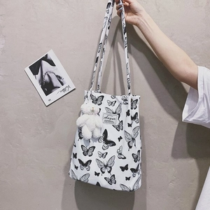 Close-up of leopard canvas tote bag featuring black butterfly print and plush bear charm
