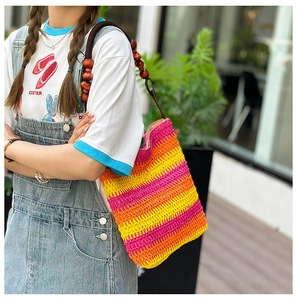 Close-up of rainbow woven straw bucket bag with elegant wooden bead handle detail