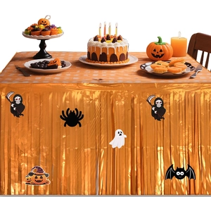 Golden foil fringe table skirt with Halloween spider and pumpkin cutouts on a party table
