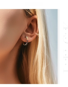 Close-up of gold hoop earrings with rainbow heart accents worn by a model