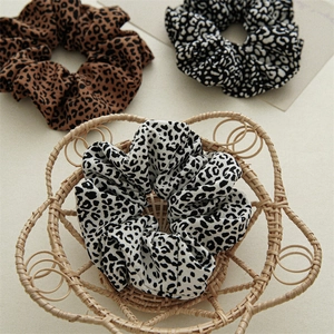 Close-up of leopard print scrunchies in a woven basket showing soft fabric texture