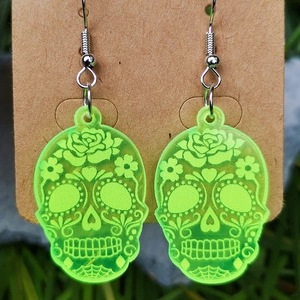 Detail view of fluorescent green sugar skull earrings made of acrylic on brown card