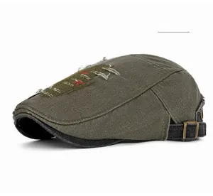 Détail de la casquette plate vert armée avec texture usée et coutures rouges en X