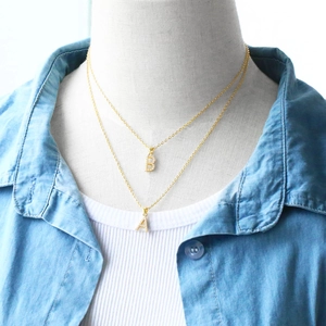 Detail of double-layered gold-tone necklaces with A and B initial pendants on a mannequin