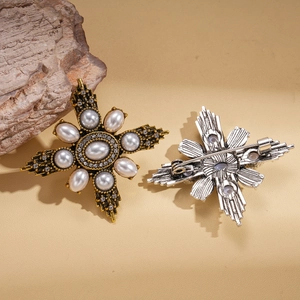 Vintage gold and silver cross star brooches with pearls and crystals on beige surface