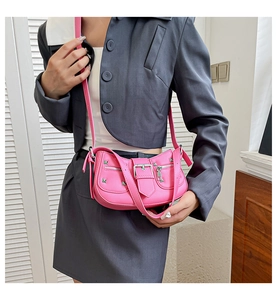 Detail of bright pink punk-style shoulder bag featuring silver rivets and metal hardware