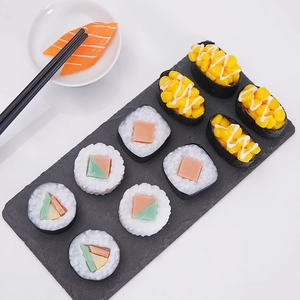 Realistic PVC sushi models set with salmon and seaweed rolls on a dark slate board