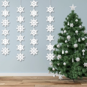 Vertical white paper snowflake garlands hanging beside a decorated Christmas tree for winter decor