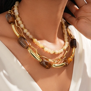 Close-up of bohemian layered necklace with amber resin blocks and cream beads
