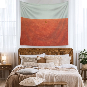 Abstract landscape wall tapestry showing orange desert dunes and blue sky in a bedroom