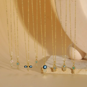 Gold-plated Evil Eye necklace collection with Hamsa and key pendants on stone display
