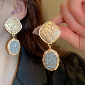 Detailed view of vintage gold earrings with embossed portrait and grey stone inlay