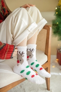 Détail de chaussettes de Noël blanches en polaire corail avec motif de renne