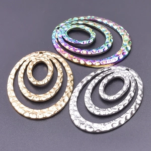 Detailed view of concentric oval jewelry charms with hammered texture in gold silver rainbow