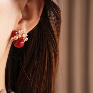 Detail view of red pearl and zircon flower stud earrings with gold plating on model