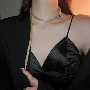 Close-up of golden snake choker featuring sparkling rhinestones and green gem eyes