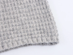 Macro detail of grey knit cardigan fabric with sparkling silver threads and ribbed texture