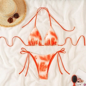 Detailed flat lay of orange tie-dye bikini with beach hat and sunglasses accessories