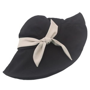Dettaglio cappello da sole nero a tesa larga con elegante fiocco beige e bordo ondulato