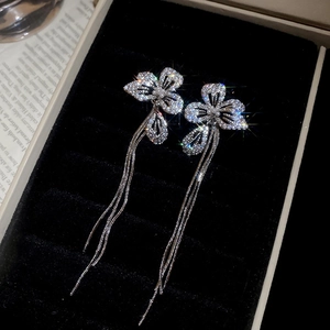 Detailed close-up of zircon flower earrings with long fringe tassels on velvet