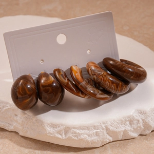 Detail of 3-pair set of amber tortoiseshell resin hoop earrings on a display stand