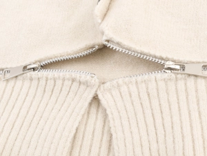 Détail du cardigan blanc cassé montrant la texture laineuse et la fermeture éclair argentée