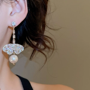 Macro view of gold bow earrings with shimmering zircons and round pearl drop