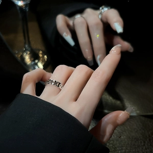 Close-up of a silver geometric ring with black zircon stone on a finger in dark lighting
