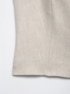 Detailed macro shot of light beige linen fabric texture and hem stitching on vest