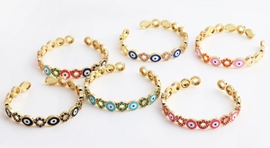 Macro shot of colorful enamel evil eye charms and floral zircon insets on gold bracelets