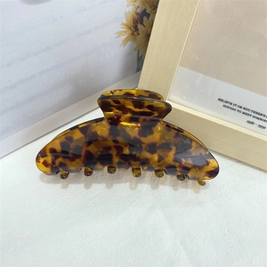 Close-up of tortoise shell pattern acetate hair claw clip on a wooden frame